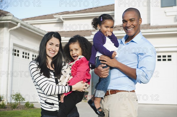 Proud parents and daughter standing in driveway