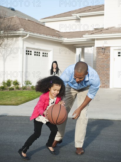 Father and daughter playing basketball in road