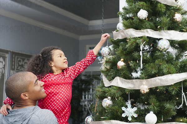 Father and daughter decorating Christmas tree