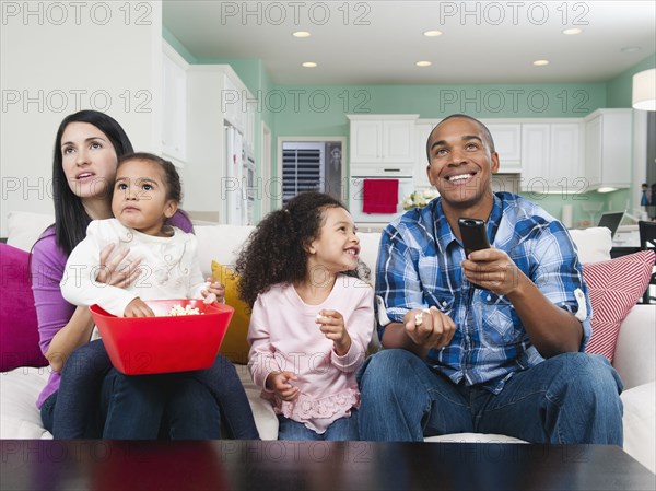 Family sitting on sofa watching television