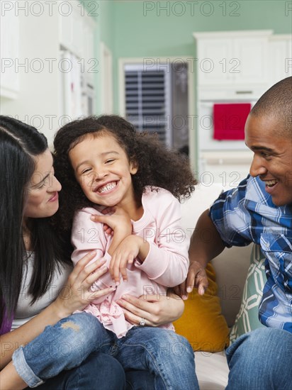 Parents tickling daughter