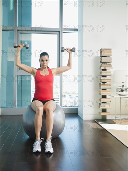 Mixed race woman exercising with dumbbells