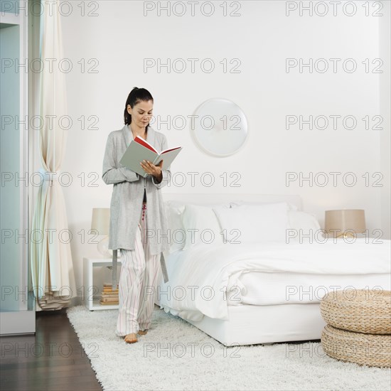 Mixed race woman reading book in bedroom