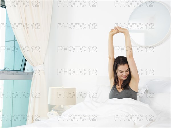 Mixed race woman stretching in bed