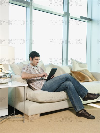 Caucasian man using digital tablet in living room