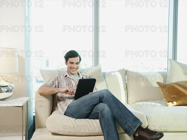 Caucasian man using digital tablet in living room