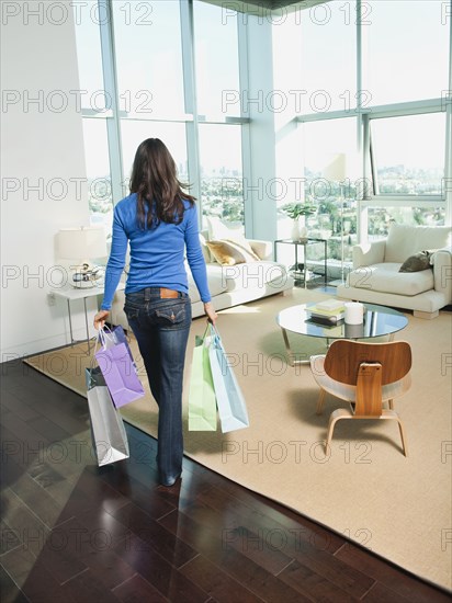 Mixed race woman carrying shopping bags in living room
