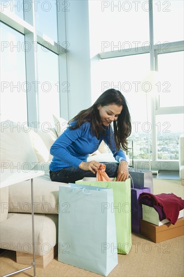 Mixed race woman emptying shopping bags in living room