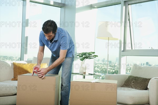 Caucasian man taping cardboard box in living room