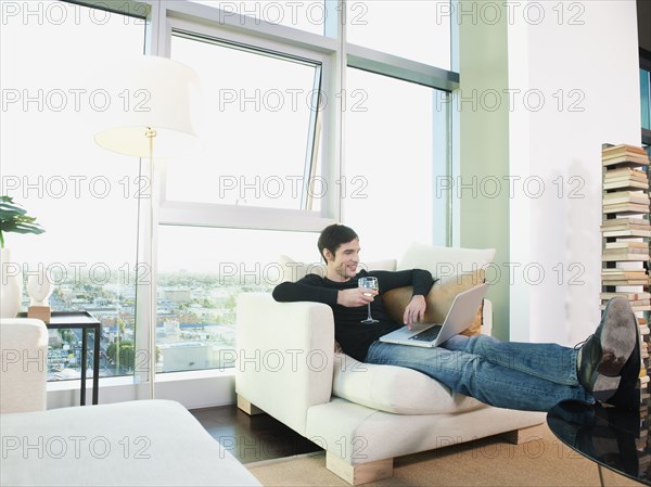 Man drinking wine and using laptop