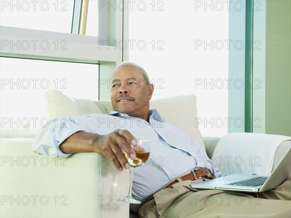 Black man drinking wine and reading book