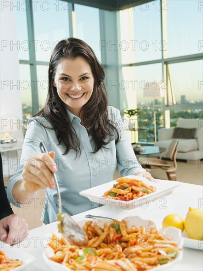 Woman serving pasta at table