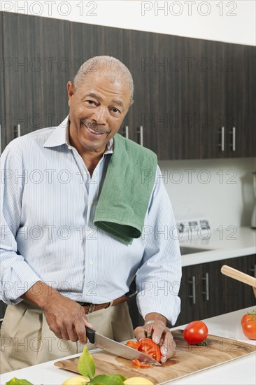 Black man slicing tomatoes in kitchen