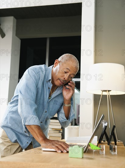 Black man talking on cell phone and using laptop