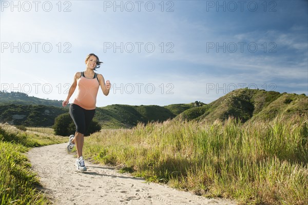 Pregnant Hispanic woman running in remote area