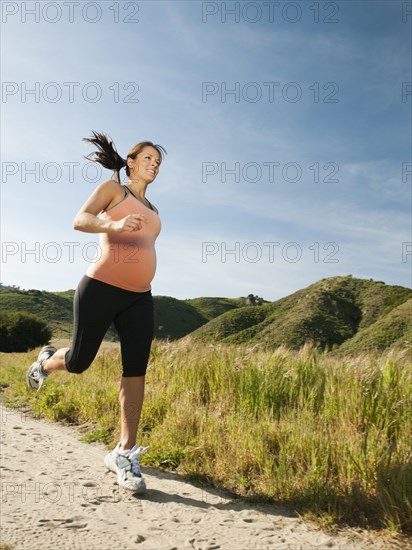 Pregnant Hispanic woman running in remote area