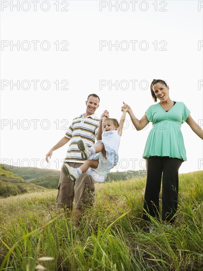 Happy parents swinging daughter in field