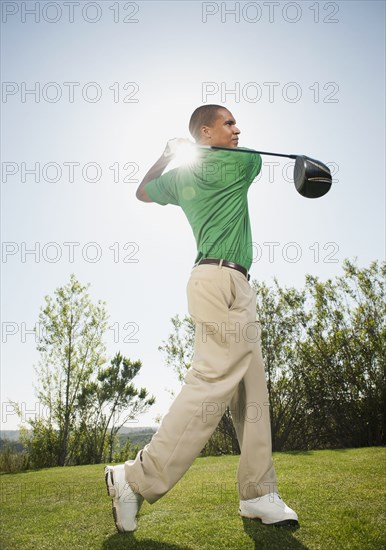 Black golfer swinging golf club