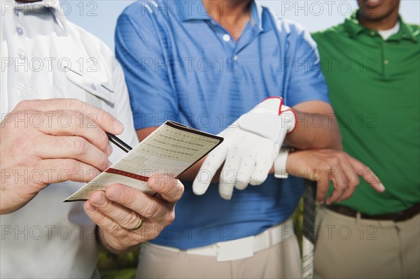 Golfer standing with friends writing in golf score card