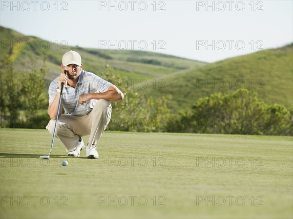 Caucasian golfer checking the ground on golf course