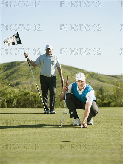 Caucasian golfer placing golf ball on course