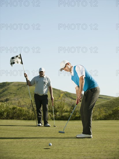 Caucasian golfer putting on golf course