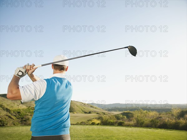 Caucasian golfer swinging golf club