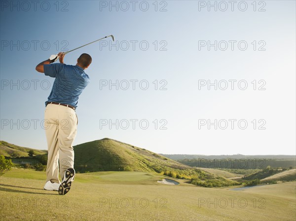 Black golfer swinging golf club