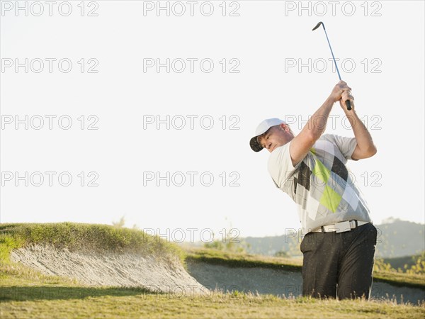 Caucasian golfer hitting ball out of bunker