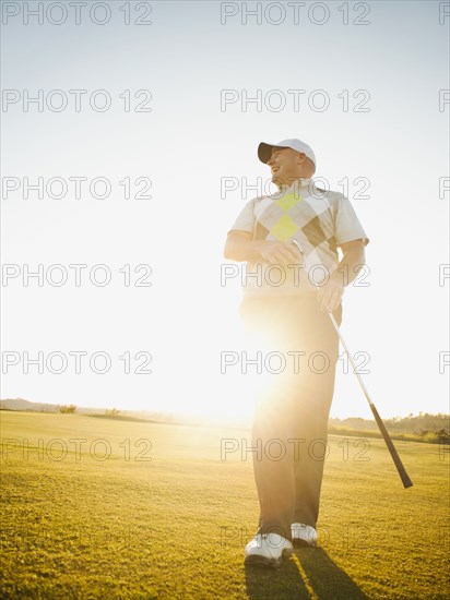 Caucasian man walking on golf course with golf club