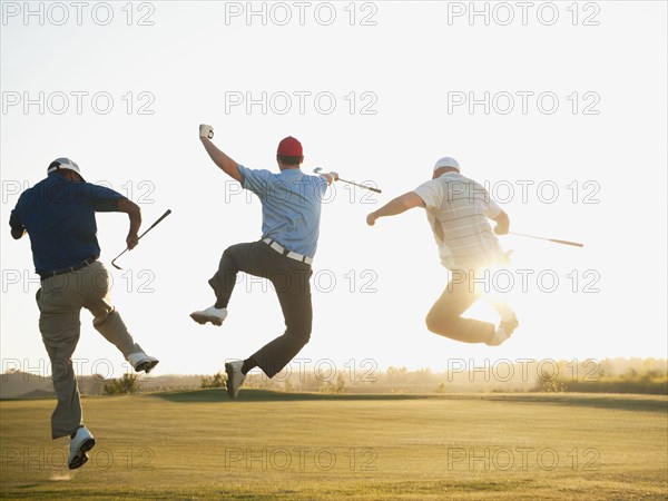 Excited golfers jumping in mid-air on golf course