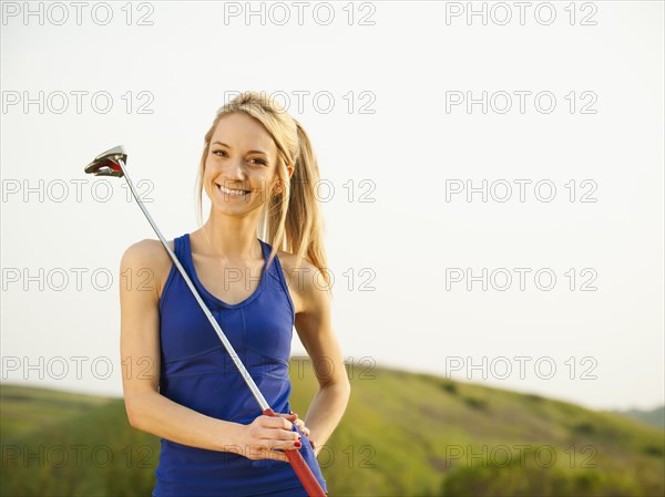 Caucasian woman holding gold club