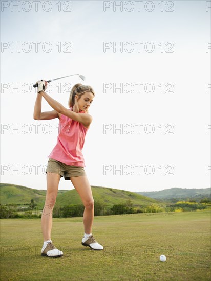 Caucasian woman swinging golf club on golf course
