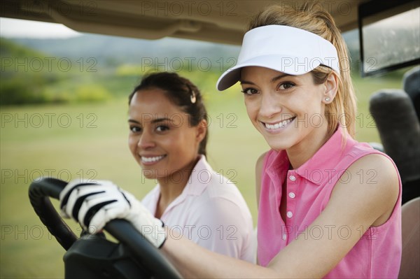 Women driving golf cart on golf course