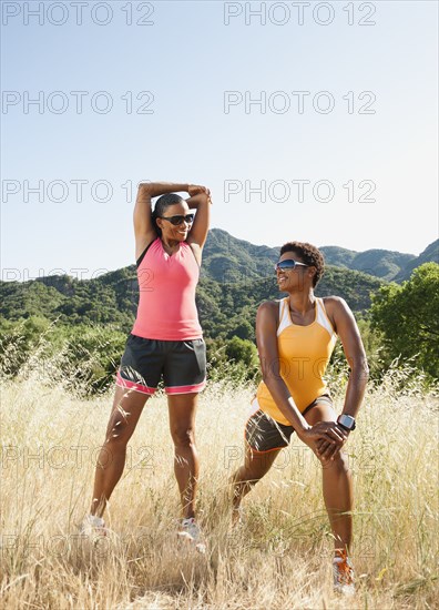 Runners stretching together in field before exercise