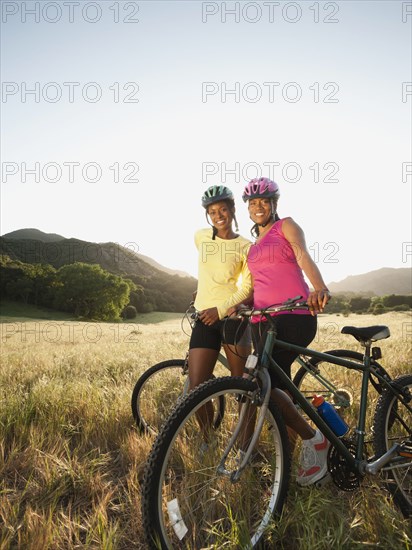 Friends standing in field with mountain bikes