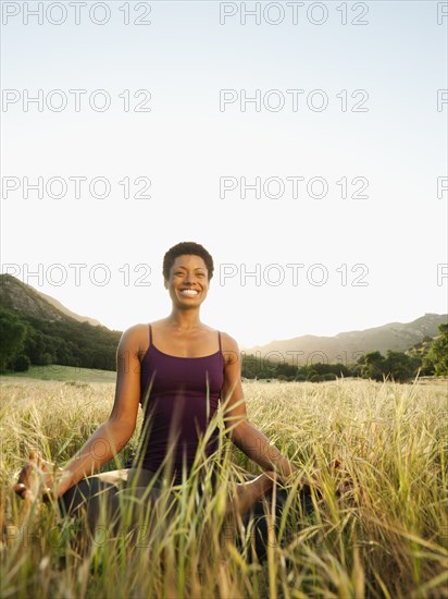 Mixed race woman practicing yoga in remote field