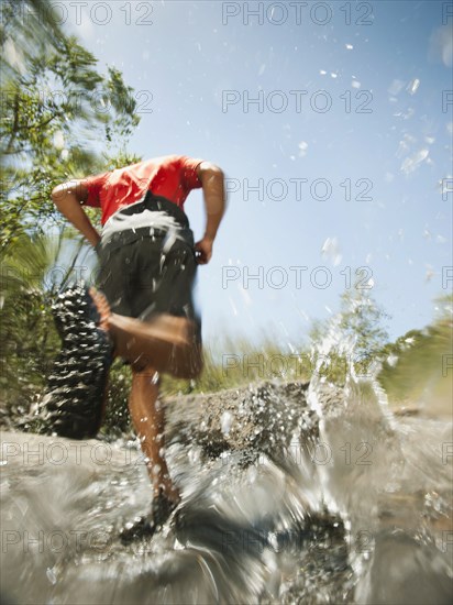 Mixed race man running through stream