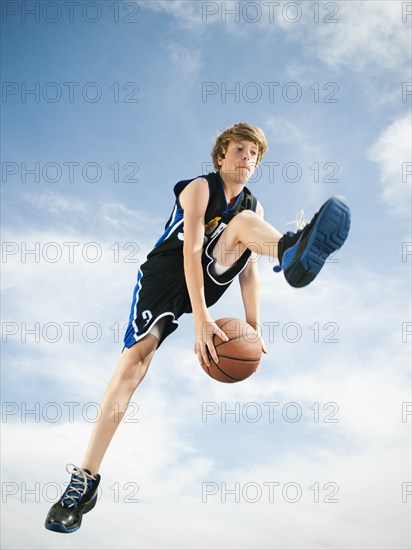 Caucasian teenager playing basketball