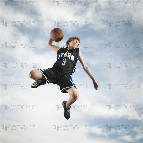 Caucasian teenager playing basketball