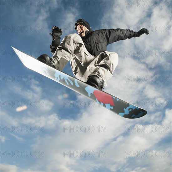 Caucasian man on snowboard in mid-air