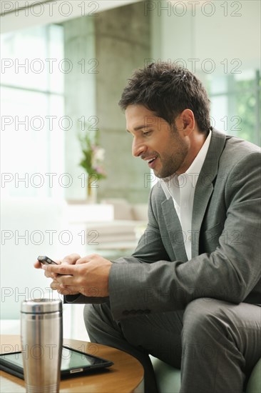 Mixed race businessman text messaging on cell phone