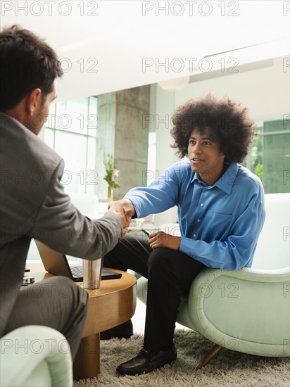 Businessmen snaking hands in lobby