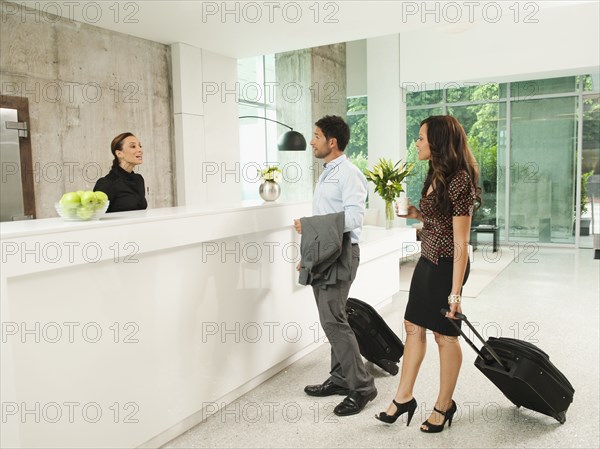 Business people arriving at hotel reception area