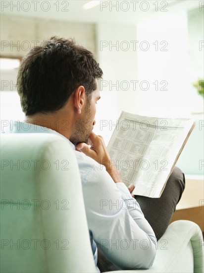 Mixed race businessman reading newspaper