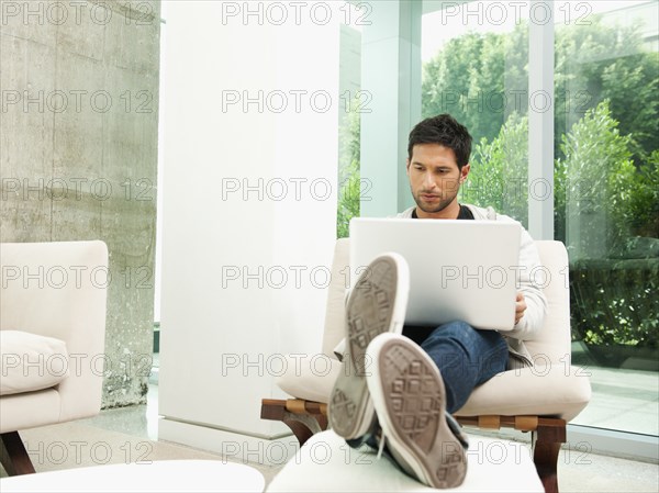 Mixed race man using laptop in living room