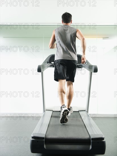 Mixed race man running on treadmill