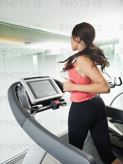 Mixed race woman running on treadmill