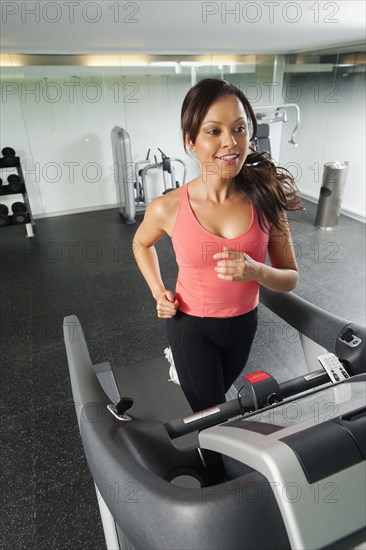 Mixed race woman running on treadmill