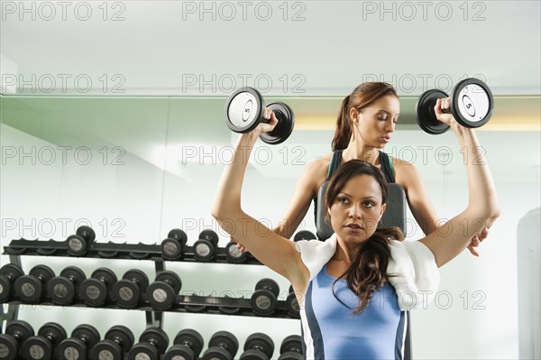 Trainer helping woman to use dumbbells